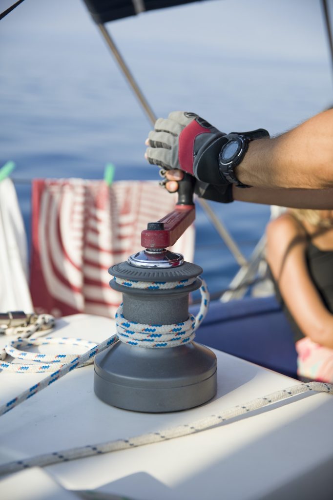 Sailing crew member pulling rope on sailboat